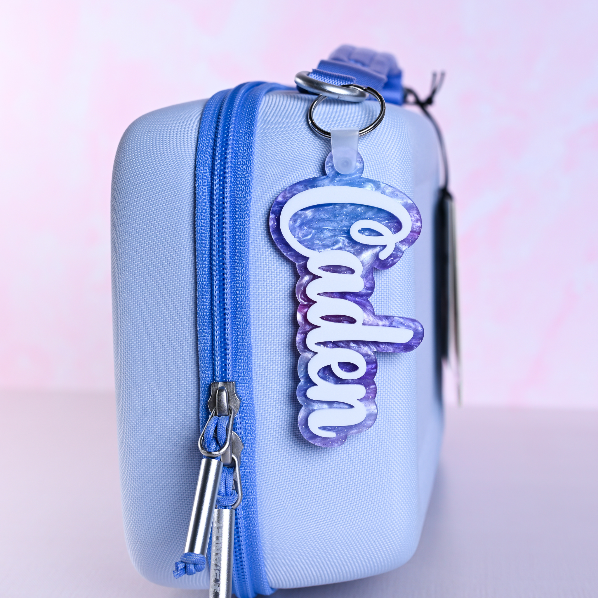 Personalized bag tags showing custom name engraving on durable acrylic with key ring attachment on a lunch box