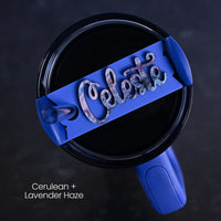 Blue tumbler accessory shown on top of a Stanley Quencher H2.0 tumbler personalized with 'Celeste' name written in a purple and dark blue swirly acrylic on top of a Cerulean  background