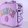 Personalized bag tags showing custom name engraving on durable acrylic with key ring attachment on a lunch box
