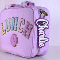 Personalized bag tags showing custom name engraving on durable acrylic with key ring attachment on a lunch box