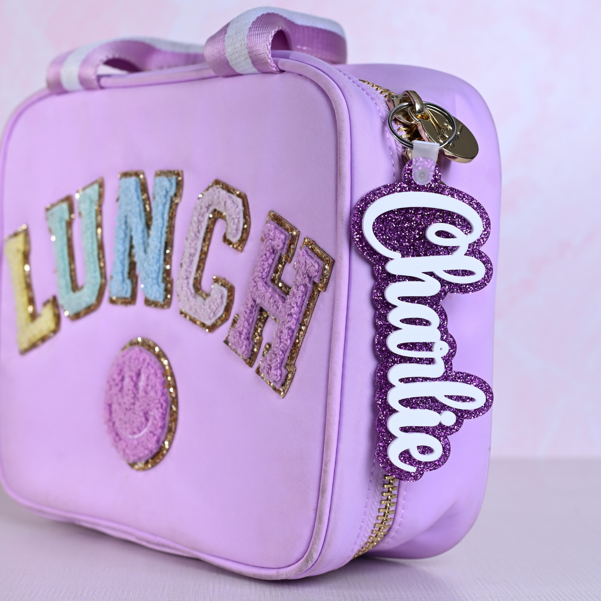 Personalized bag tags showing custom name engraving on durable acrylic with key ring attachment on a lunch box