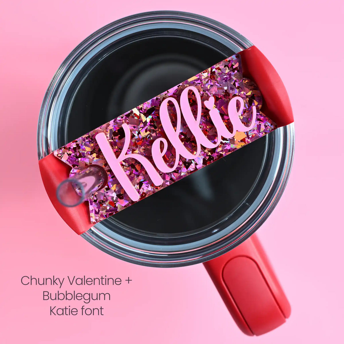 The top of a stanley tumbler shown with pink and red chunky glitter acrylic with the name Kellie written in cursive in bubblegum pink acrylic font.