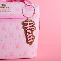 Love Shack Fancy Ibiza Sunset floral-patterned bag with a gold glitter and bubblegum bag tag
