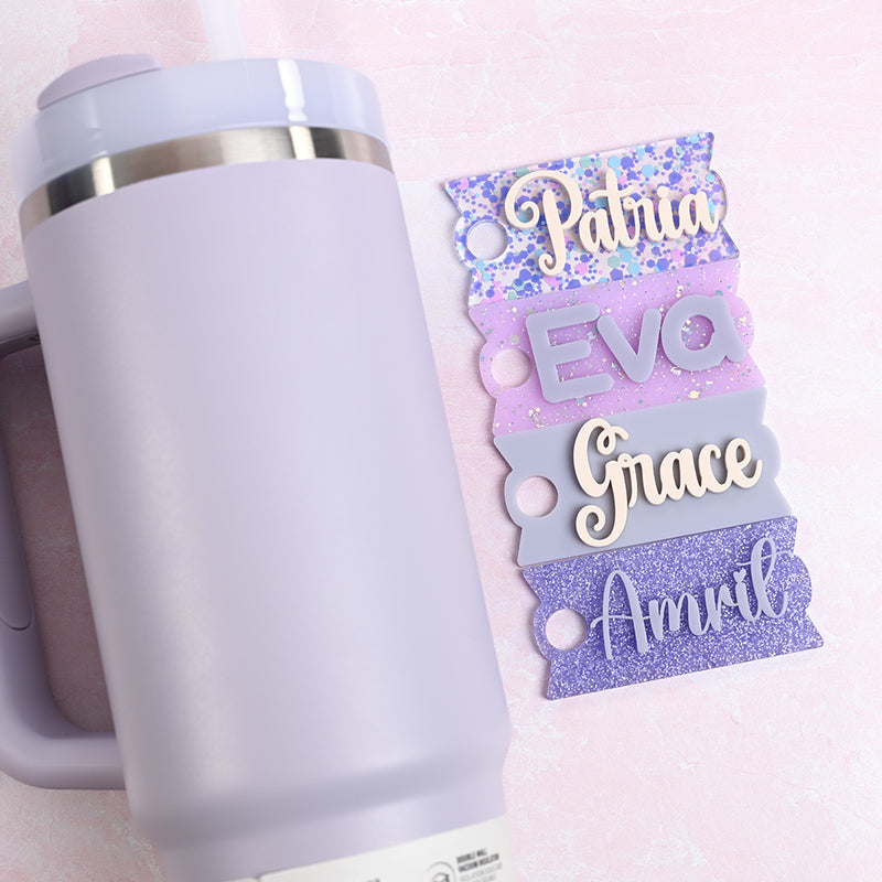 White tumbler with personalized name tags on a light pink background
