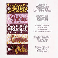 A collection of acrylic Topper Tag name plates designed for Stanley Quencher tumblers in burgundy, pink, and gold color tones.