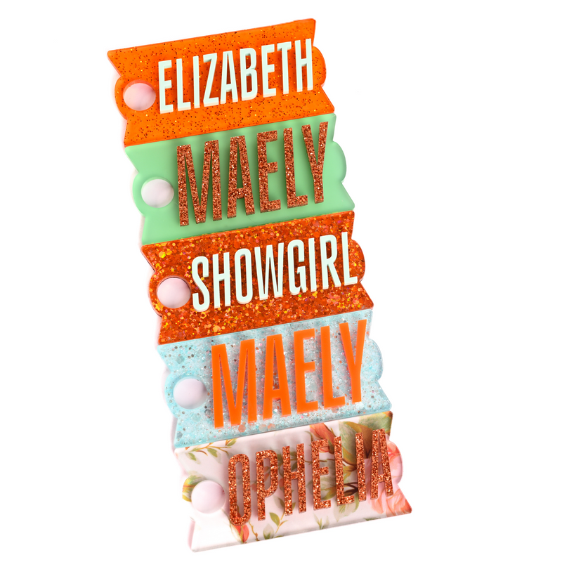 The life of a showgirl themed Stanley name tags for stanley quencher tumblers in orange shimmer with mint, Spearmint with bronze glitter, pumpkin sparkle with mint, aquamarine sparkle with halloween orange, and Ophelia's Flowers with bronze glitter