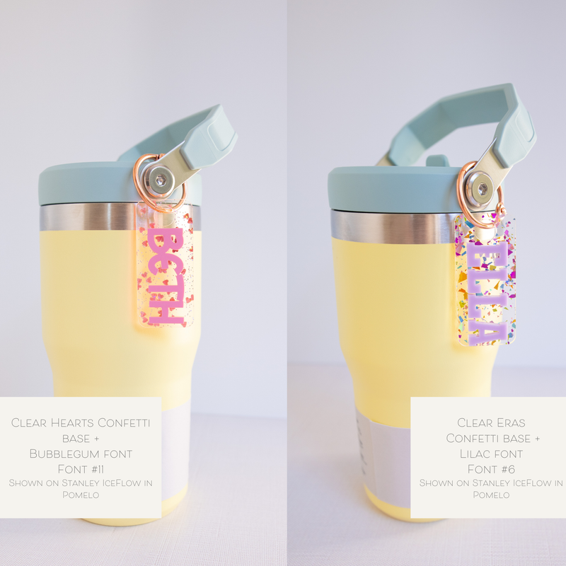 A collection of personalized tumbler charms in various colors and with different names printed on them, attached to a keychain ring.