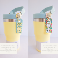 A collection of personalized tumbler charms in various colors and with different names printed on them, attached to a keychain ring.