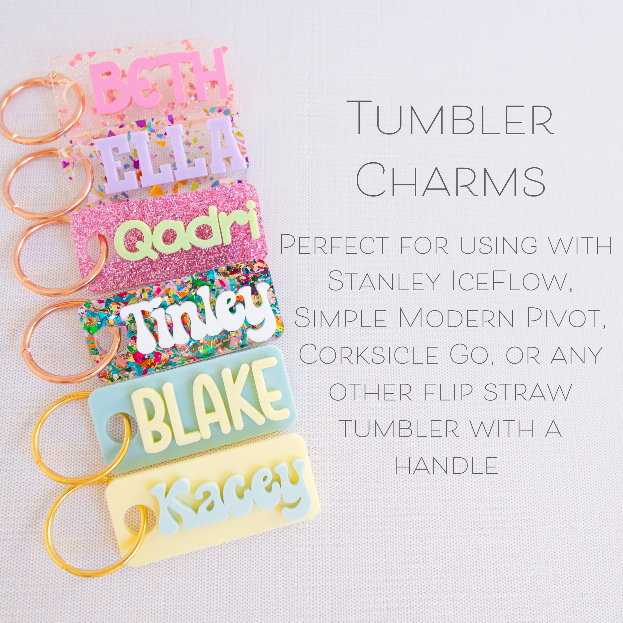 A collection of personalized tumbler charms in various colors and with different names printed on them, attached to a keychain ring.