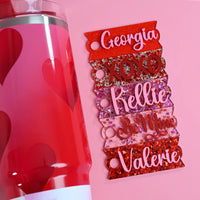 A lay flat picture of five example Topper Tag for Stanley Quencher styles made from various red and pink glitter acrylics. A red and pink Stanley tumbler with hearts from Target is shown next to the Topper Tag for the purpose of color comparison.